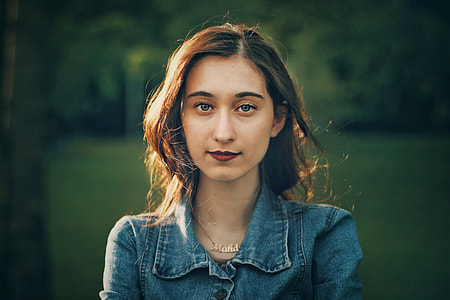 selective focus photo of woman wearing blue denim collared top and gold-colored necklace thumbnail