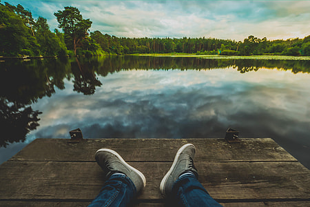 Man with his feet in shot relaxing at a lake thumbnail