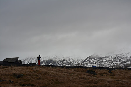 silhouette of man looking at brown mountain covered by snow thumbnail