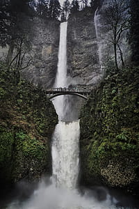 people passing on grey arch bridge near waterfall thumbnail