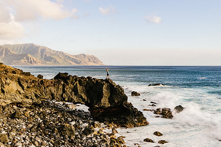 man standing on rock near body of water thumbnail