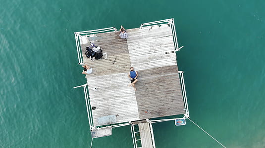 Person Lying on Brown Wooden Platform on Body of Water thumbnail