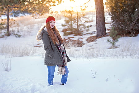 woman standing on snow covered road near trees thumbnail