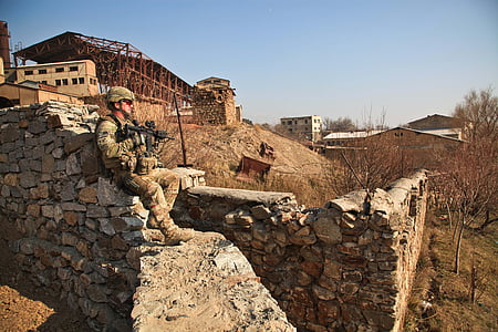 soldier sitting on rocks during daytime thumbnail