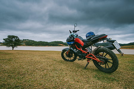 Red and Black Standard Motorcycle on Green Grass Field thumbnail