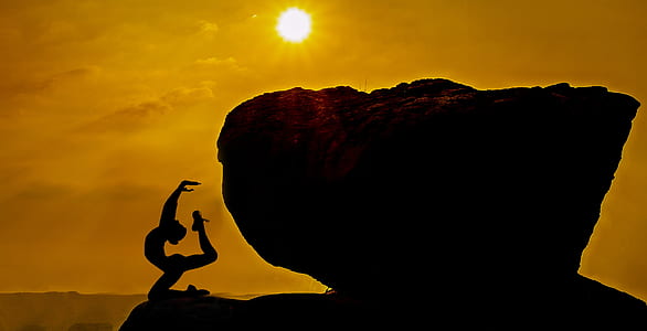 silhouette of woman doing yoga beside stone during golden hour thumbnail