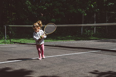 girl holding brown wooden tennis racket taken at daytime thumbnail