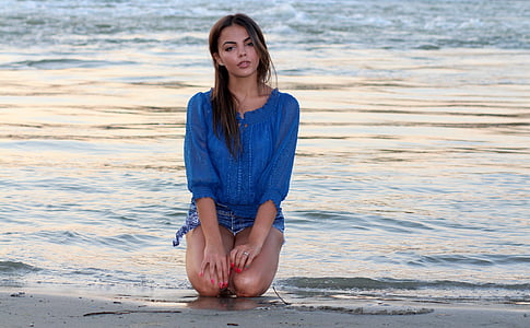 woman kneeling on beach during daytime thumbnail