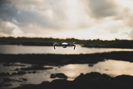 white and black quadcopter flying under white clouds thumbnail