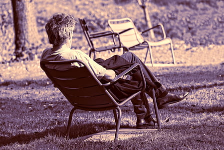 sepia photography of man sitting on chair in lawn thumbnail