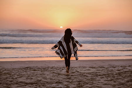 woman running towards sea waves at sunset thumbnail