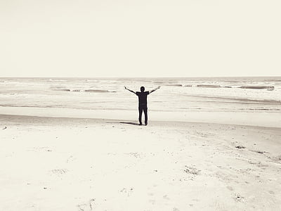 man rising hand standing on seashore at daytime thumbnail