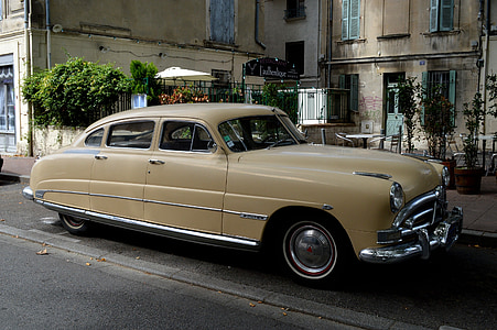 classic yellow sedan on concrete road near buildings at daytime thumbnail