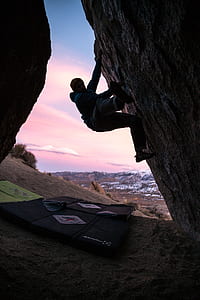 man climbing on rock wall during daytime thumbnail