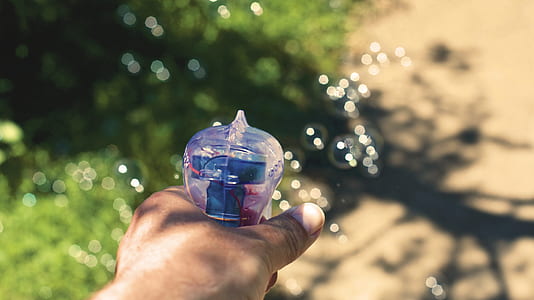 Person Holding White and Blue Plastic Bubble Dispensing Gun thumbnail