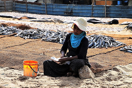 person sitting beside orange bucket on sands thumbnail