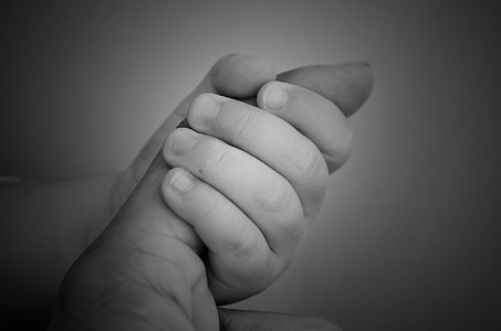 grayscale photo of baby holding index finger thumbnail