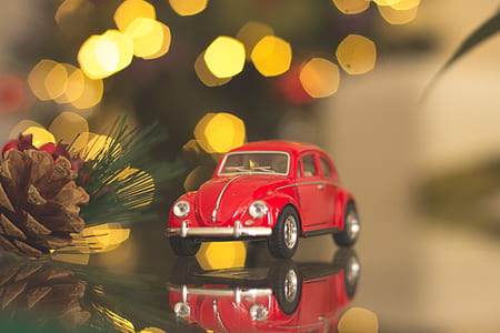 tilt-shift photography of red beetle car toy on mirrored surface thumbnail