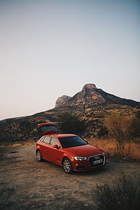red Audi 5-door hatchback parked at near grass field and mountain during daytime thumbnail