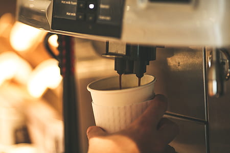 person holding cup getting coffee on machine thumbnail