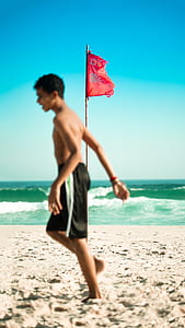 man in black shorts walking on seashore thumbnail