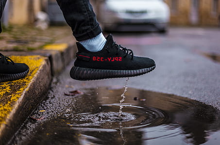 person wearing bred adidas Yeezy Boost 350 V2 shoes stepping on body of water thumbnail