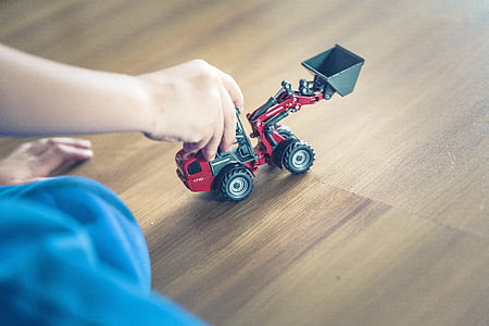 person holding red and gray heavy equipment toy thumbnail