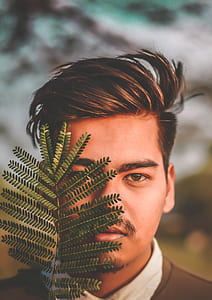 man standing next to green leaves thumbnail