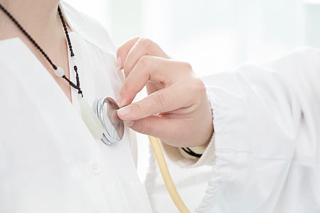 person wearing beaded black necklace and person using stethoscope thumbnail