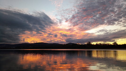 silhouette photo of trees near body of water at golden hour thumbnail