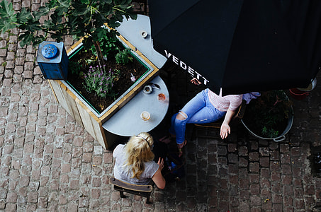 woman sitting on brown wooden chair near plant during day time thumbnail