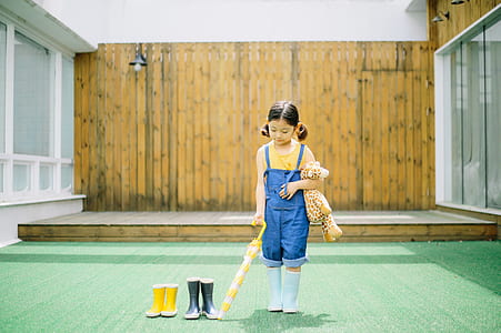 girl holding yellow umbrella and giraffe plush toy thumbnail