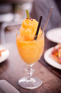 clear footed drinking glass filled with orange liquid on table thumbnail