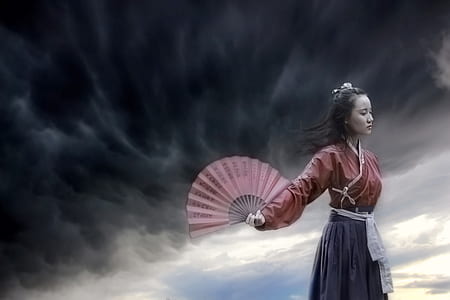 woman wearing purple and gray long-sleeved dress and holding hand fan with cloudy sky as background thumbnail