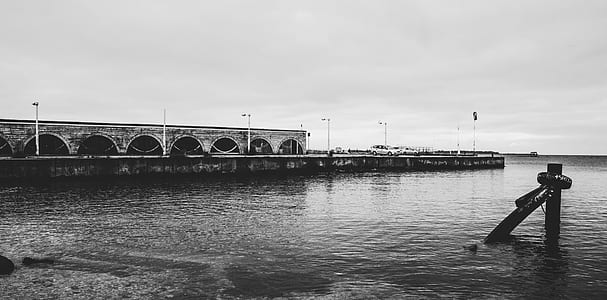 Grayscale Photo of Body of Water Near White Concrete Wall thumbnail
