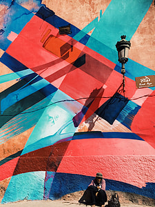 male sitting beside black plastic bag leaning at graffiti wall thumbnail