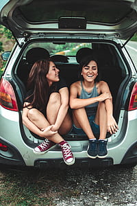 two women sitting on vehicle trunk thumbnail