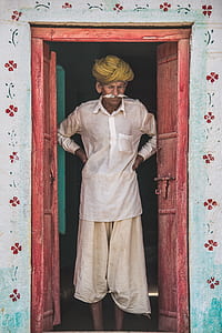 man in white dress shirt and shorts standing on door during daytime thumbnail