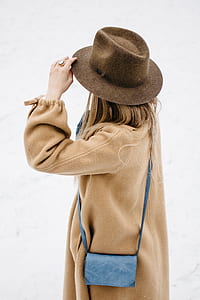 woman wearing brown coat and fedora hat during daytime thumbnail