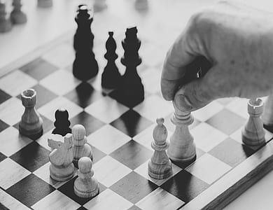 grayscale photo of man playing chess thumbnail