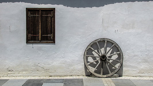 gray wooden wheel beside wall at daytime thumbnail