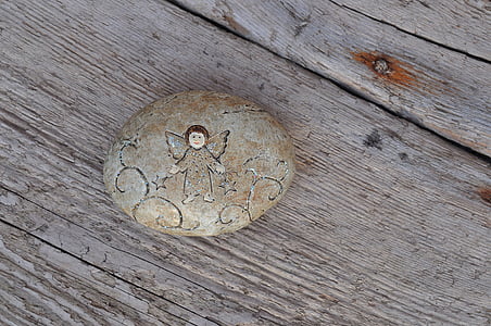 brown angel engraved stone placed on wooden surface thumbnail
