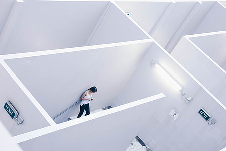 woman in white sleeveless top standing leaning on white wall thumbnail