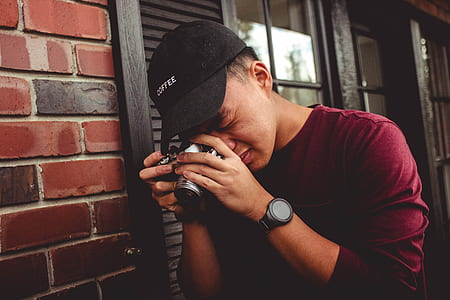 man holding camera near wall while taking photo thumbnail