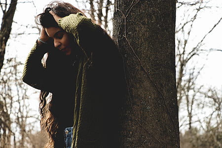 woman holding her head beside tree thumbnail