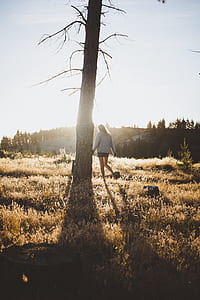 woman in grey sweater with shorts standing beside tree thumbnail