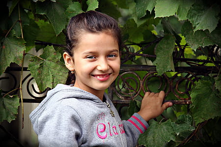 girl wearing gray hoodie standing beside plant thumbnail