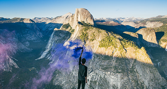 man standing on high ground facing gray mountains at daytime thumbnail