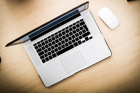 black and gray laptop computer beside white Apple Mighty Mouse on brown wooden surface thumbnail
