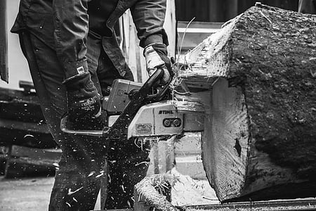 grayscale photography of person cutting log using chainsaw thumbnail